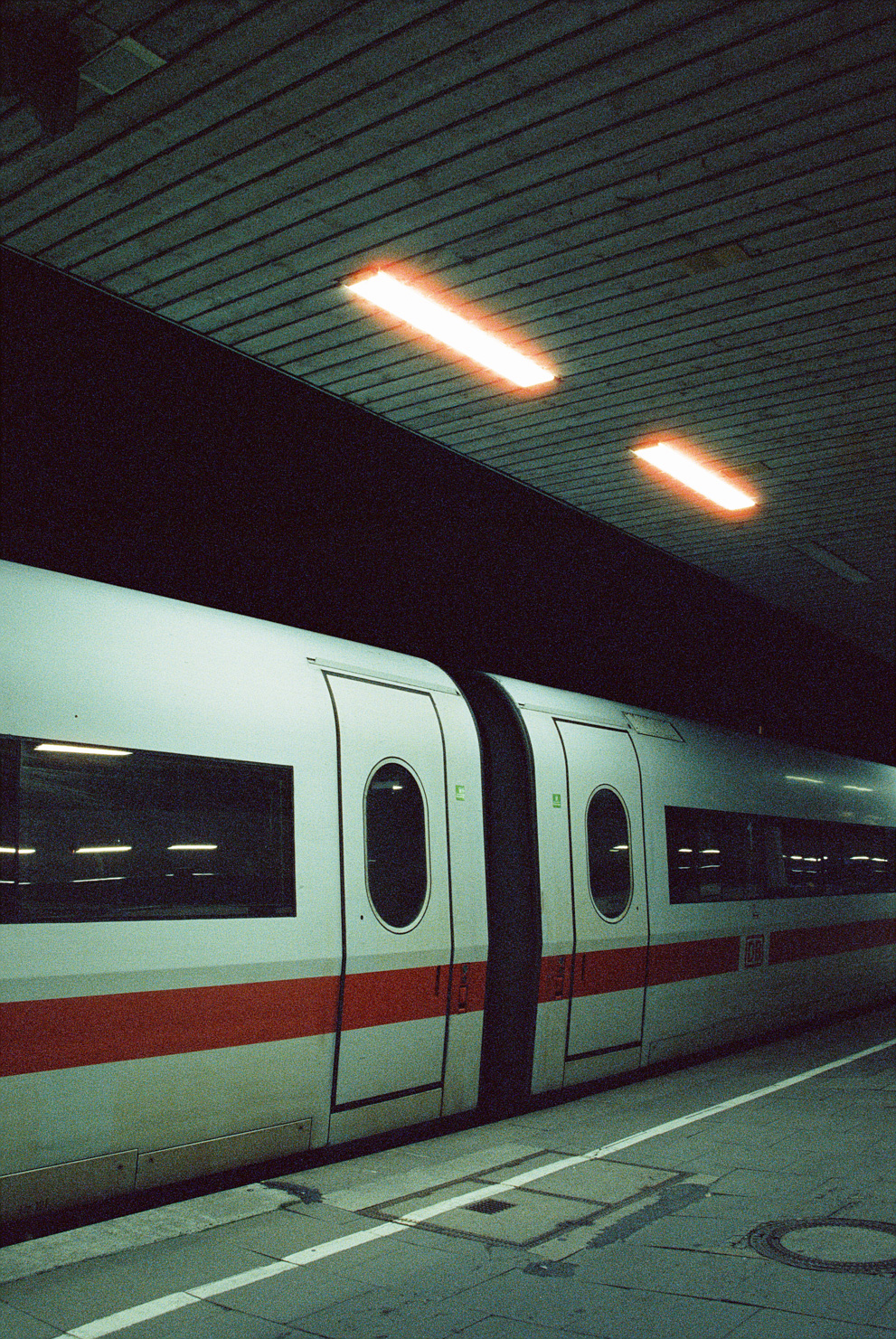 A Intercity Express train parked at the station at night.  Shot on Cinestille 800T.