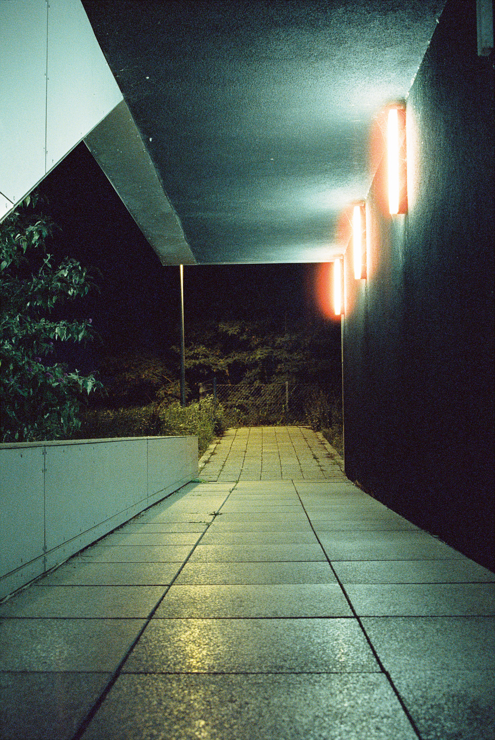 A stone corridor with mixed lighting during night. Shot on Cinestille 800T.