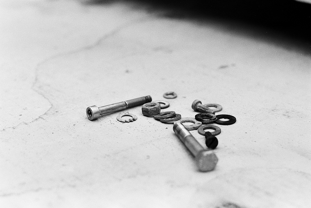 Macro of a few nuts and bolts on a concrete block. Shot on Fomapan 100 classic.