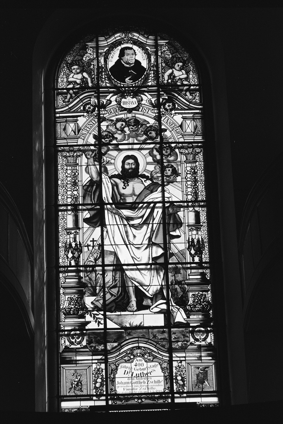 The colored window in the St Mary's Church (Marienkirche) in Grossenhain showing Jesus and Martin Luther. Shot on Fomapan 200 creative.